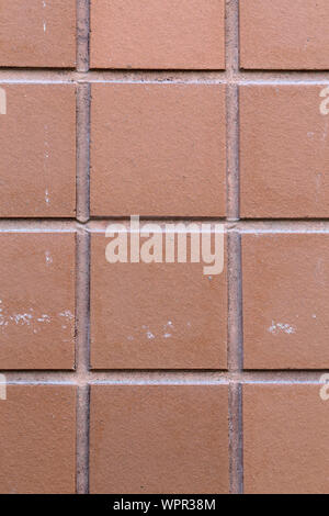 Red / orange exterior wall of a building. This wall is made of square shaped mosaic tiles and has lovely texture. Closeup photo of architecture. Stock Photo