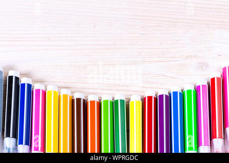 Multi-colored markers on a white wooden chtol, top view, place for text Stock Photo
