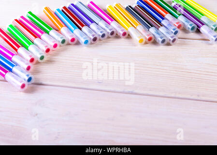 Multi-colored markers on a white wooden chtol, top view, place for text Stock Photo
