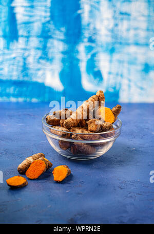 turmeric powder in jar dish on blue background Stock Photo