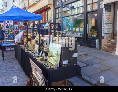 Antiques and artwork displayed for sale on a stall in Guildford Antique & Brocante Street Market, High Street, Guildford, Surrey, southeast England Stock Photo