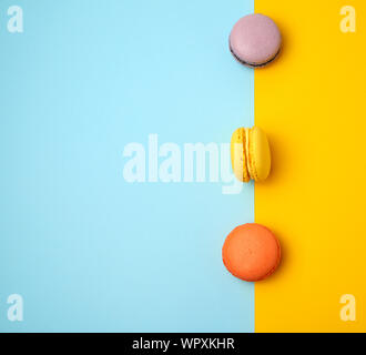 multi-colored baked round macarons on a colored background, flat lay Stock Photo