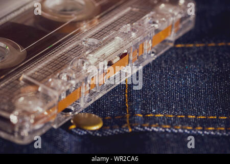 Cassette tape audio on jeans fabric in darkness. Concept of vintage 90s music player. Stock Photo