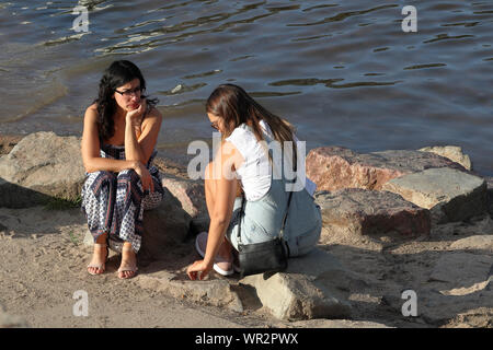 Denver, Colorado - September 7, 2019: Two young women having a conversation by South Platte River on a sunny afternoon in Denver, Colorado Stock Photo