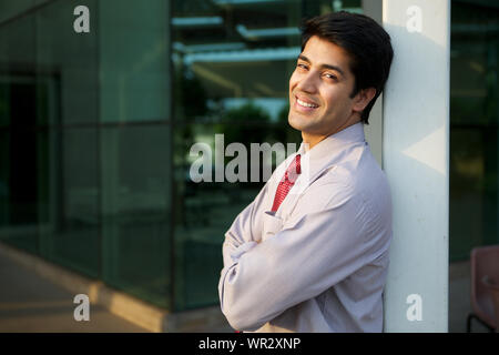 Businessman leaning against pole and smiling Stock Photo