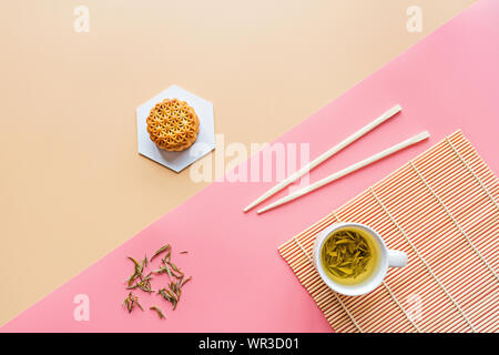 Flat lay of Chinese Festival dessert, Mid Autumn Festival Moon cake on colorful background with green tea and chopsticks. Top view, copy space, mockup Stock Photo