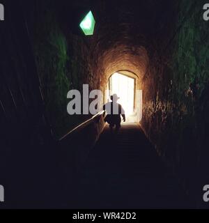 Rear View Of Silhouette Man Moving Down Steps In Tunnel