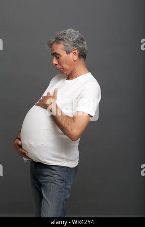 Senior man pretending to be a pregnant woman Stock Photo