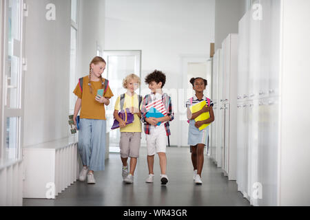 Pupils wearing backpacks waling to the classroom together Stock Photo