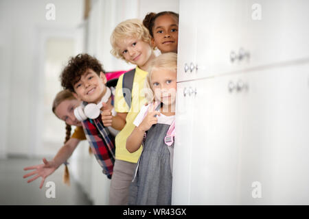 Cheerful children standing near lockers while enjoying school break Stock Photo