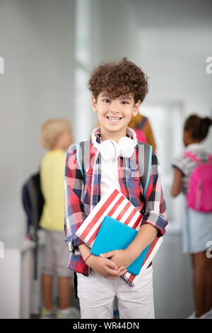 Dark-haired boy smiling while walking to classroom Stock Photo