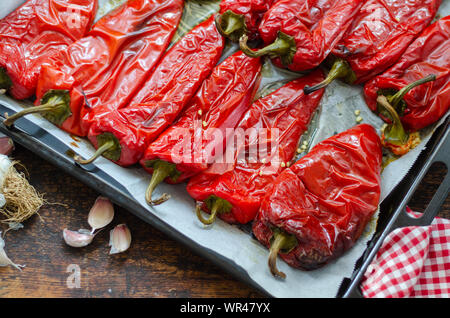 Roasted red peppers for winter preparation on wooden table. Stock Photo