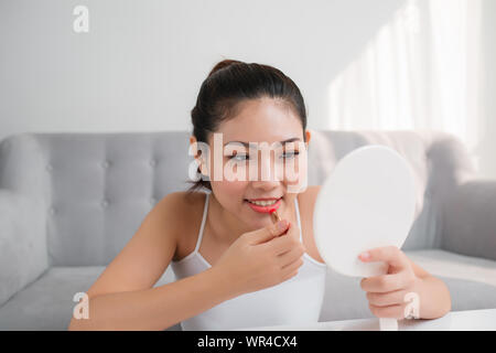 Portrait of Young Asian woman applying lipstick looking at mirror Stock Photo
