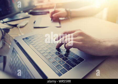 Professional graphic editor retouching images with stylus pen in hand.Retoucher processsing photos on laptop computer using tablet.Freelance photograp Stock Photo