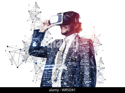 Businessman wearing VR goggles and exploring virtual reality. Man standing and touching VR headset. Studio photo businessperson in formal wear against Stock Photo