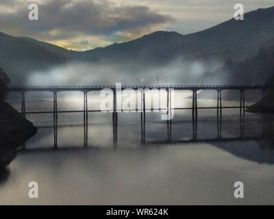 Silhouette Bridge Over River During Foggy Weather During Sunset