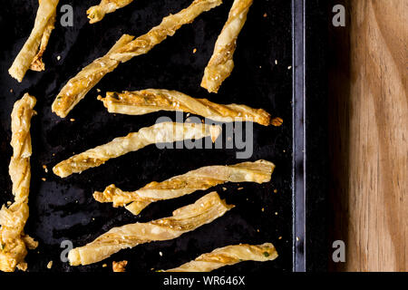 Cheesy cheese pastry straws with sesame seeds and bits of chili in oven pan  - top view photo Stock Photo