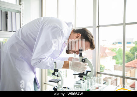 Medical Research and Scientists are working with a microscope and a tablet and Test Tubes, Micropipette and Analysis Results in a laboratory. Stock Photo
