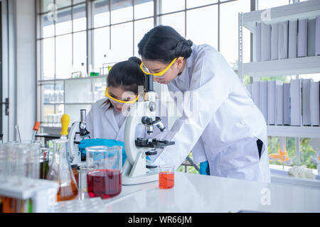 Medical Research and Scientists are working with a microscope and a tablet and Test Tubes, Micropipette and Analysis Results in a laboratory. Stock Photo