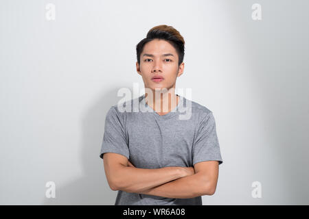 Beautiful Asian young man in casual shirt crossing his arms over chest against light white background Stock Photo