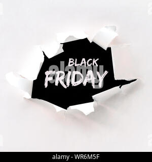 Black friday text in paper hole teared in white paper over black background. Flat lay, overhead angle, square composition Stock Photo