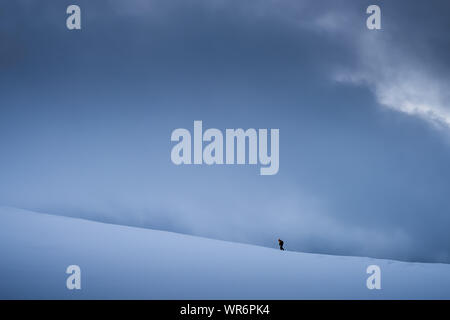 Unidentifiable person walking towards Storsteinen mountain summit and peak in the snow among the wonderful winter scenery, Norway Stock Photo