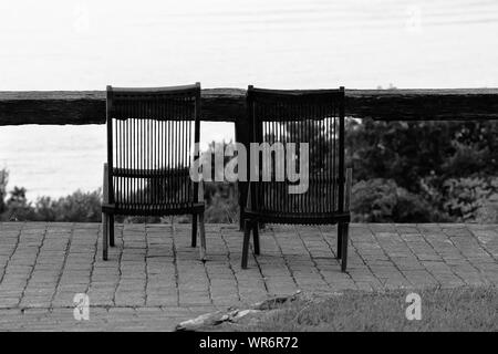 Empty Deck Chairs On Footpath Against Sea