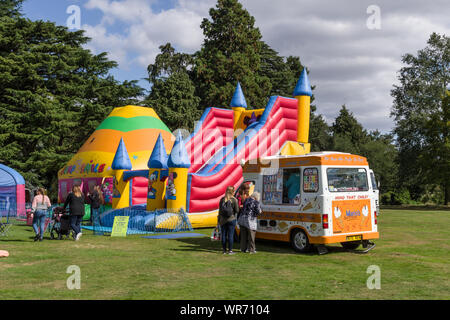 Summer in the park, a colourful bouncy castle with an ice cream van in front; Delapre Abbey, Northampton, UK