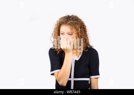 Scared and skeptical woman, keeps hands under chin, sees something terrible. Human face expressions and emotions concept. Afraid and anxious biting na Stock Photo