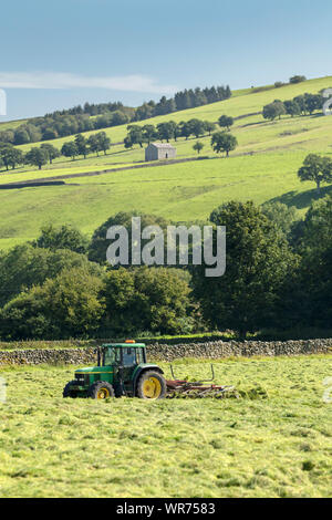A farmer near Middlesmoor in Nidderdale turning the hay on a sunny day, The Yorkshire Dales, UK. Stock Photo