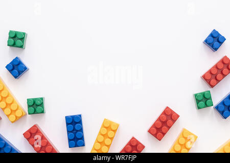 On a white background in a chaotic manner are large multi-colored childrens blocks-designer for the construction of houses and buildings of varying Stock Photo