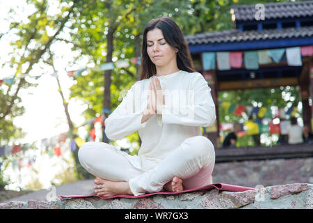 Brunette woman meditates on nature background. Yoga exercises in retreat. Stock Photo