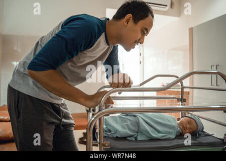 Young smiling father putting his newborn baby Stock Photo