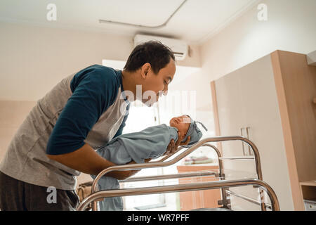 Young smiling father putting his newborn baby Stock Photo