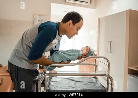 Young smiling father putting his newborn baby Stock Photo