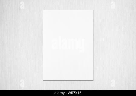 Empty white vertical rectangle poster mockup with soft shadow on neutral light grey textured background. Flat lay, top view Stock Photo