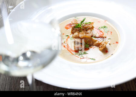Creamy white vegetable soup with roasted potato chips. Stock Photo