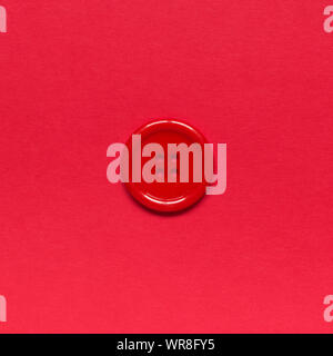 Single red sewing button on red background. Stock Photo