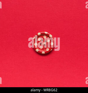 Single red sewing button with white dots on red background. Stock Photo