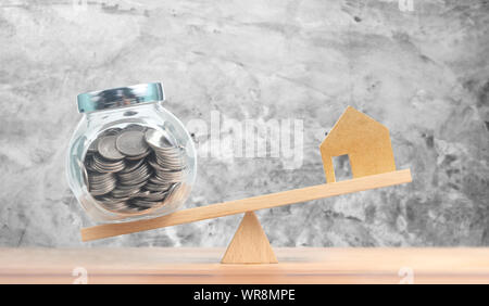 Property investment and house mortgage financial concept,Model house and money coins balancing on seesaw Stock Photo