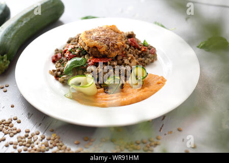 Vegetarian cooking. Colorful vegetable meatless dish. Boiled lentils with carrot puree and grilled zucchini. Stock Photo