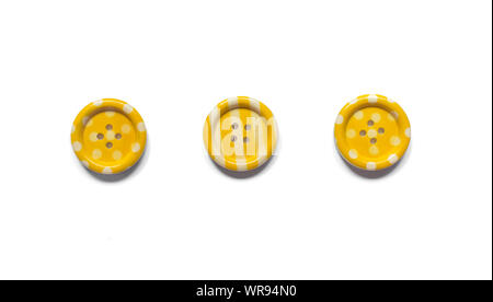 Three Various yellow sewing buttons isolated on background. Stock Photo