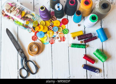 Sewing material (sewing buttons ,sccissors , threads) on old white table. High angle view Stock Photo