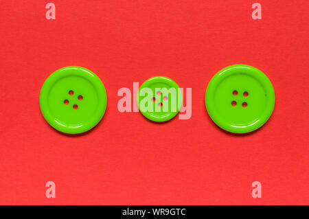 Three Various green sewing buttons  on red background. Stock Photo