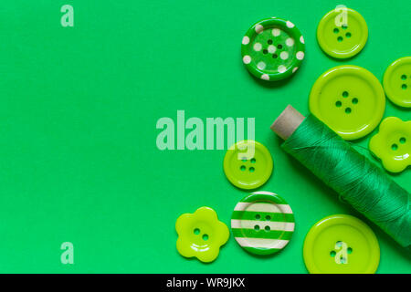 Various green sewing buttons and green thread on green background with place for text Stock Photo