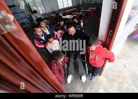 (190910) -- NANNING, Sept. 10, 2019 (Xinhua) -- Students help push disabled teacher Ruan Wenping in a wheelchair out of the classroom at Nian'en primary school in Lingyun County, south China's Guangxi Zhuang Autonomous Region, March 26, 2019. Since 2012, reporter has visited 250 teachers in remote mountain areas in Guangxi and recorded their lives. Teachers there always fill multiple roles, such as concierge and cook.  There are about 16.74 million teachers in China, a 79 percent surge from the figure in 1985 when China designated Sept. 10 as Teachers' Day, the Ministry of Education said. Stock Photo