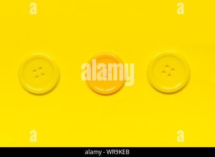 Three Various yellow sewing buttons  on yellow background. Stock Photo