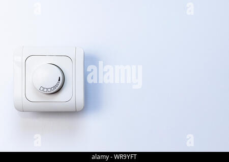 Dimmer Light Switch. Electrician switch. White rolling electricity switch on a bright wall Stock Photo