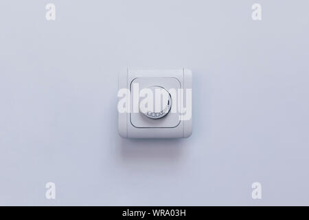 Dimmer Light Switch. Electrician switch. White rolling electricity switch on a bright wall Stock Photo