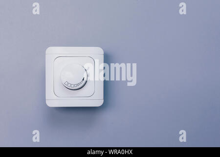 Dimmer Light Switch. Electrician switch. White rolling electricity switch on a bright wall Stock Photo